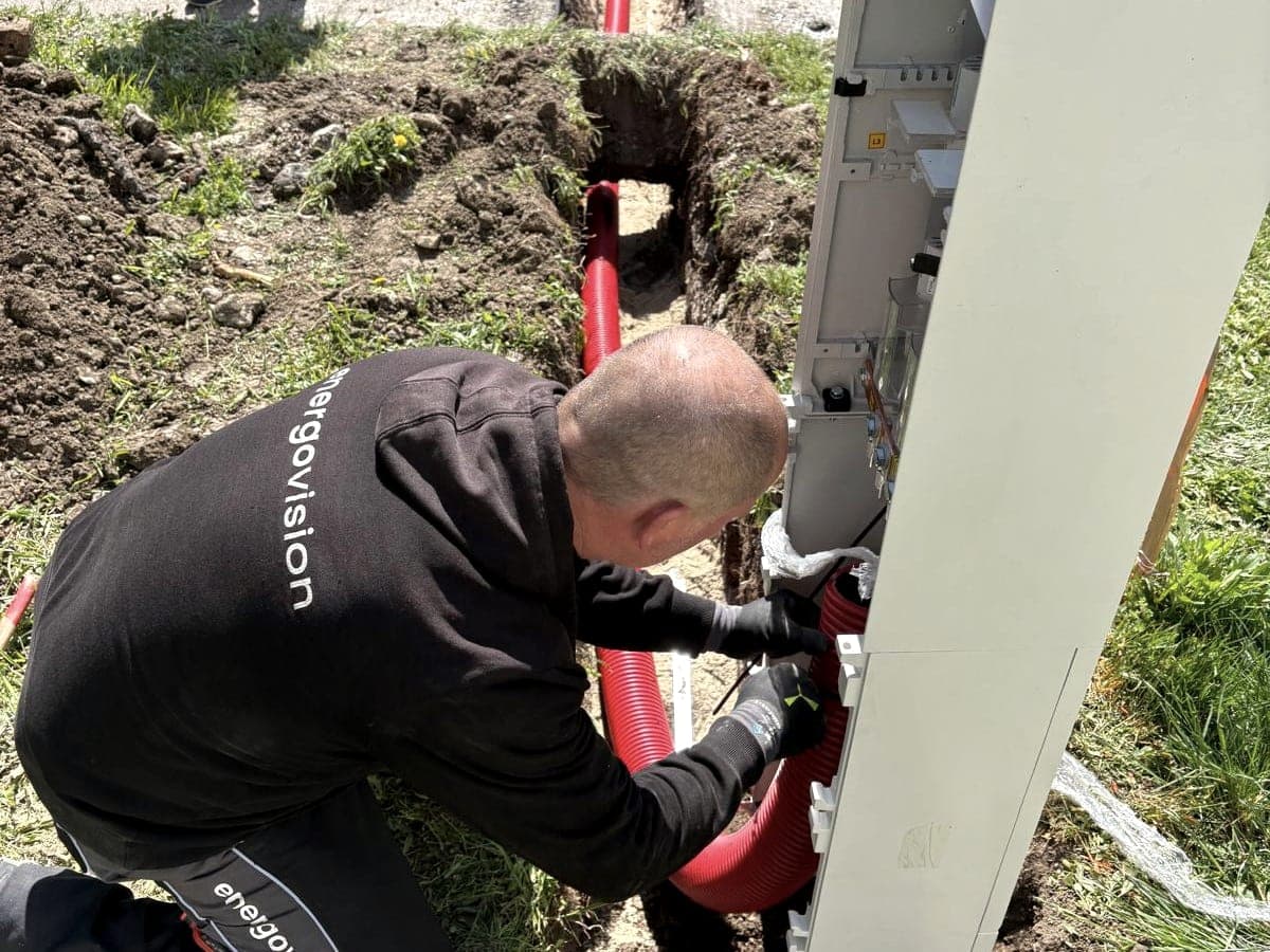 Elektrikár Energovision zapája kábel v chráničke do nového elektromerového piliera pri výkope