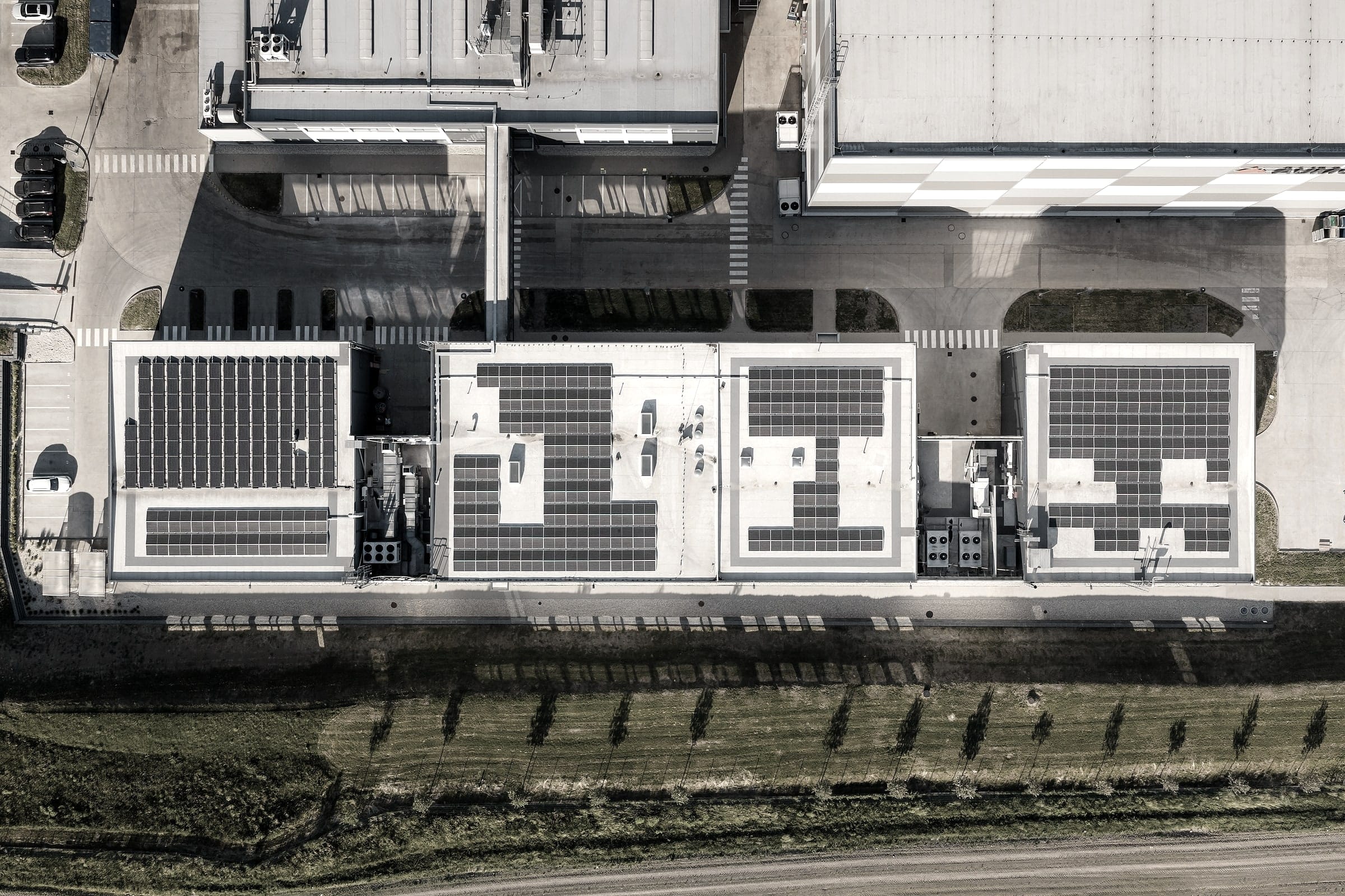 Kolmý letecký pohľad na priemyselný areál so štyrmi budovami, fotovoltikou na strechách a technologickými dvormi