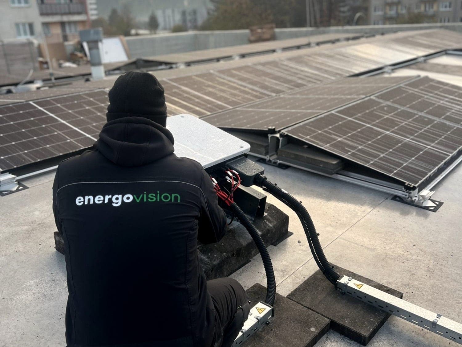 Technik Energovision zapája menič na plochej streche medzi radmi panelov