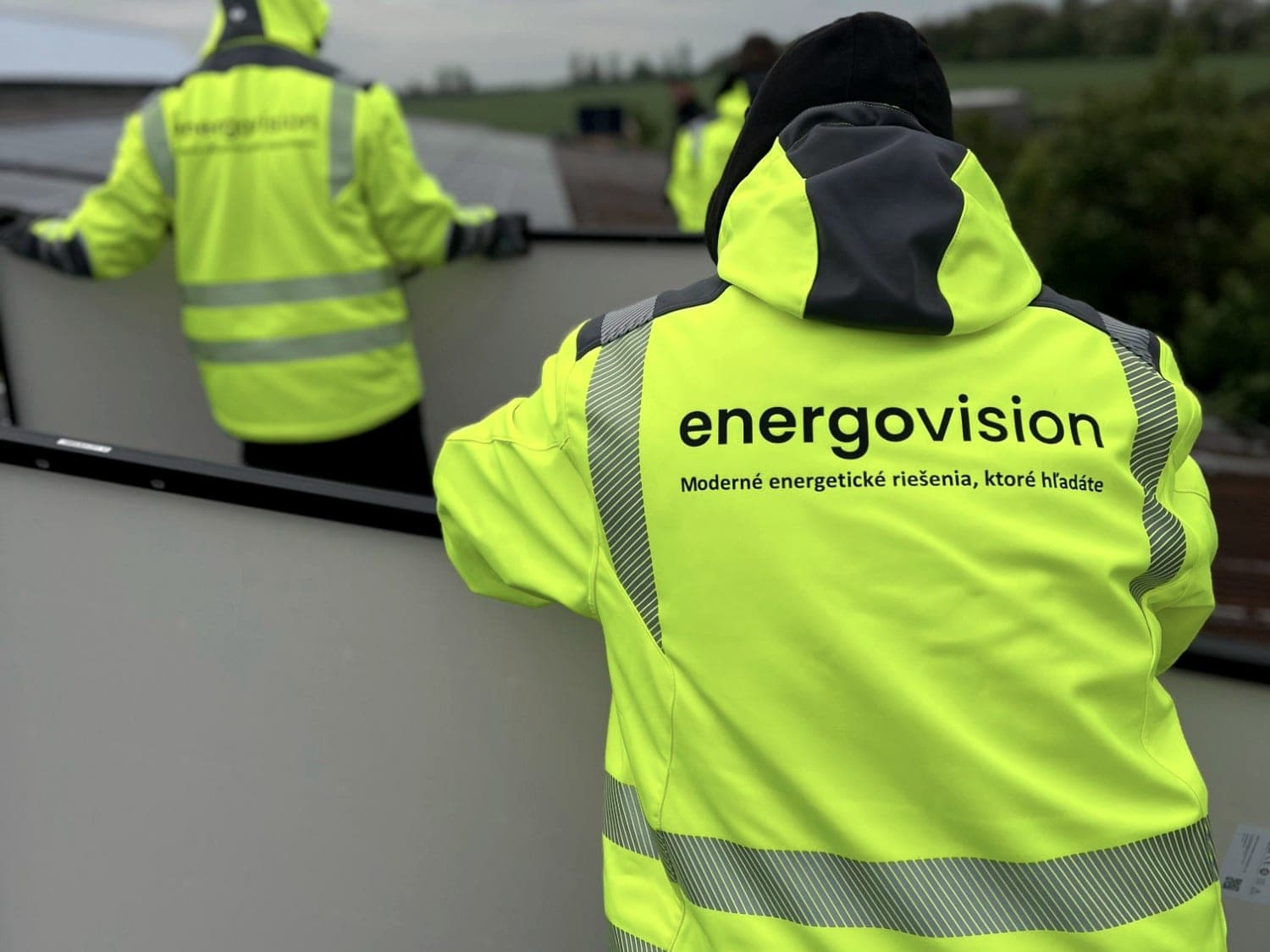 Montážny tím Energovision v reflexných bundách pri inštalácii panelov na streche